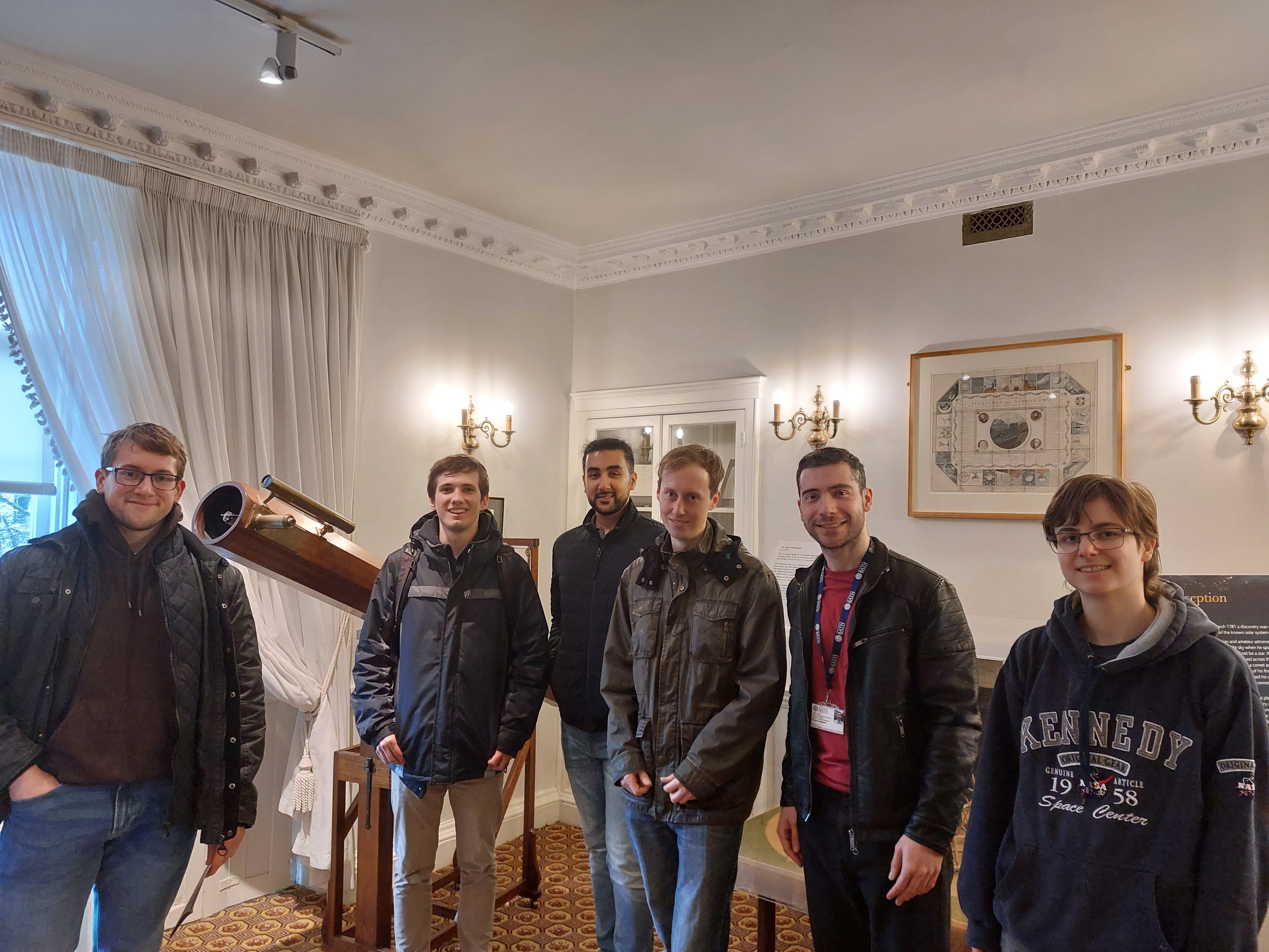 Six smiling students gather in the Herschel Museum. An old telescope can be seen behind them.